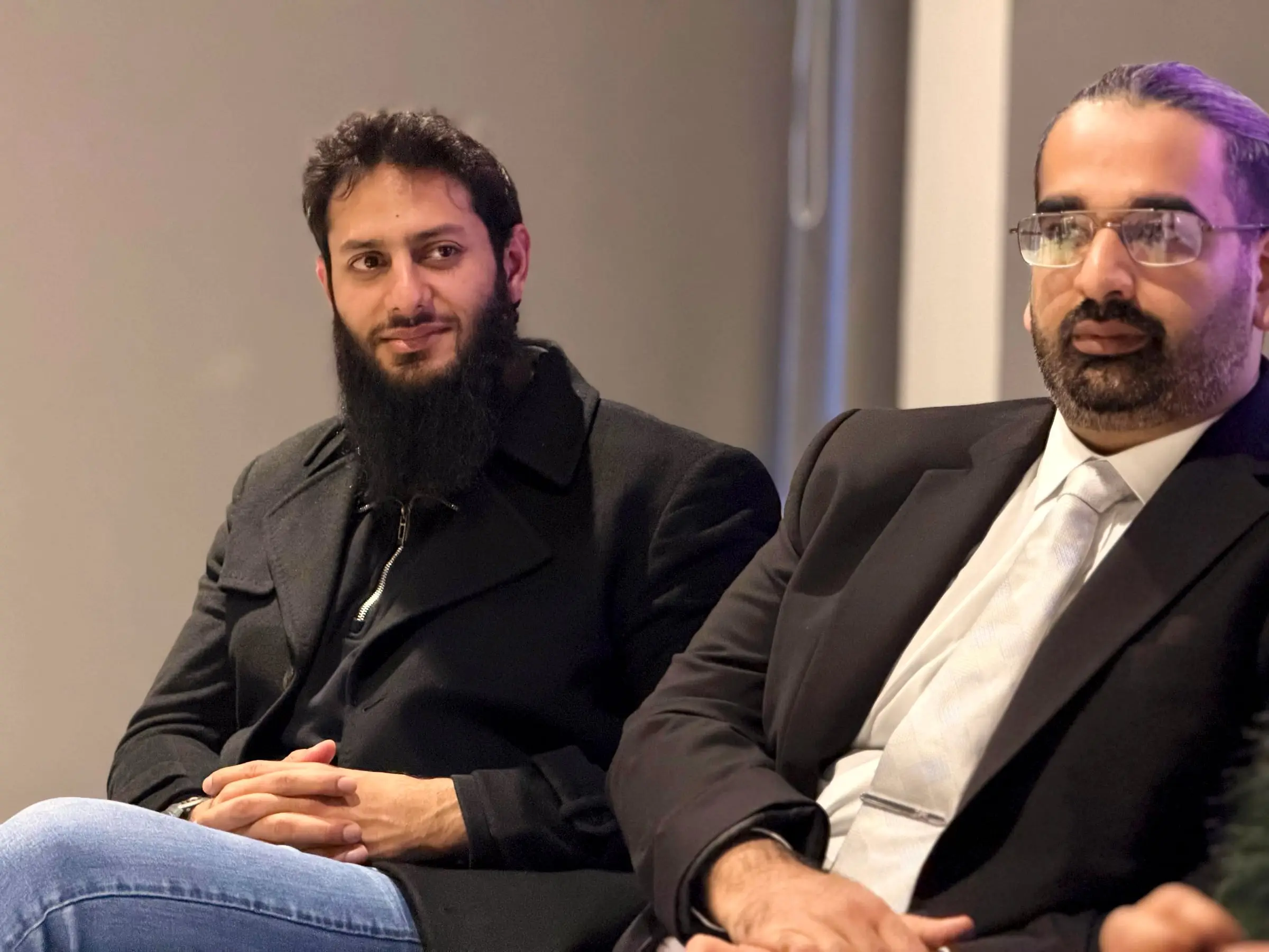 Usman seated on stage during a panel, listening
