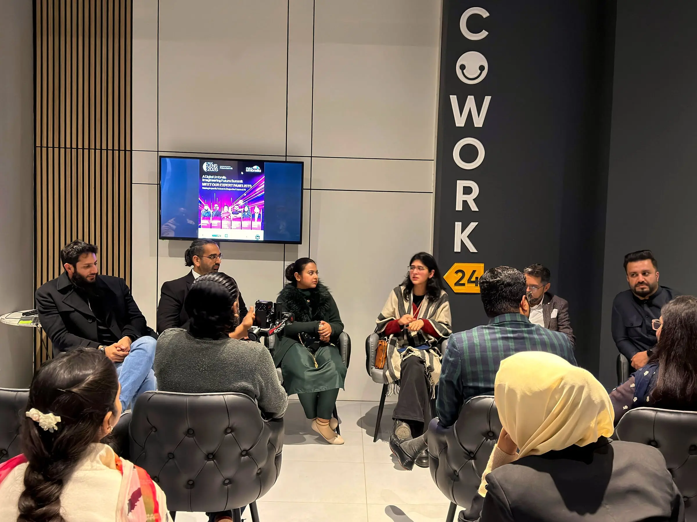 Usman seated on a panel in front of an audience