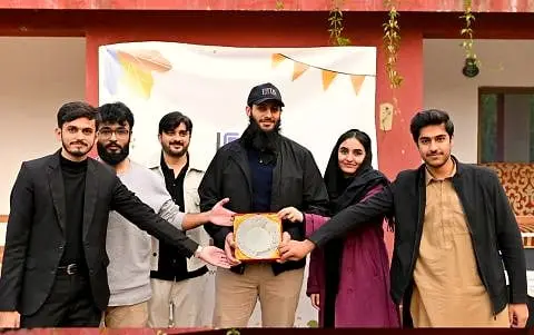 Usman holding an award shield with colleagues around him