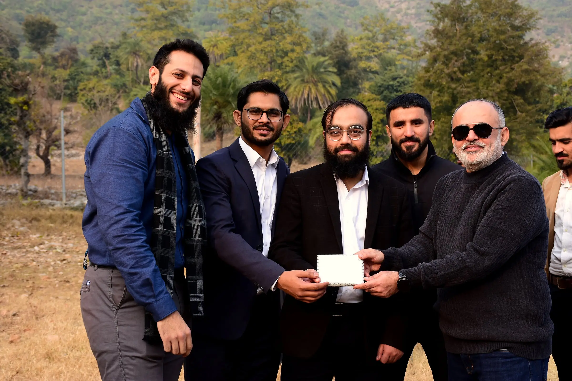 Usman with colleagues outdoors during a recognition moment